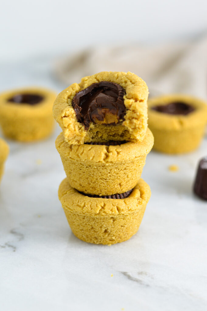 3 Dark Chocolate Peanut Butter Cookie Cups with a bite taken out of the top one.