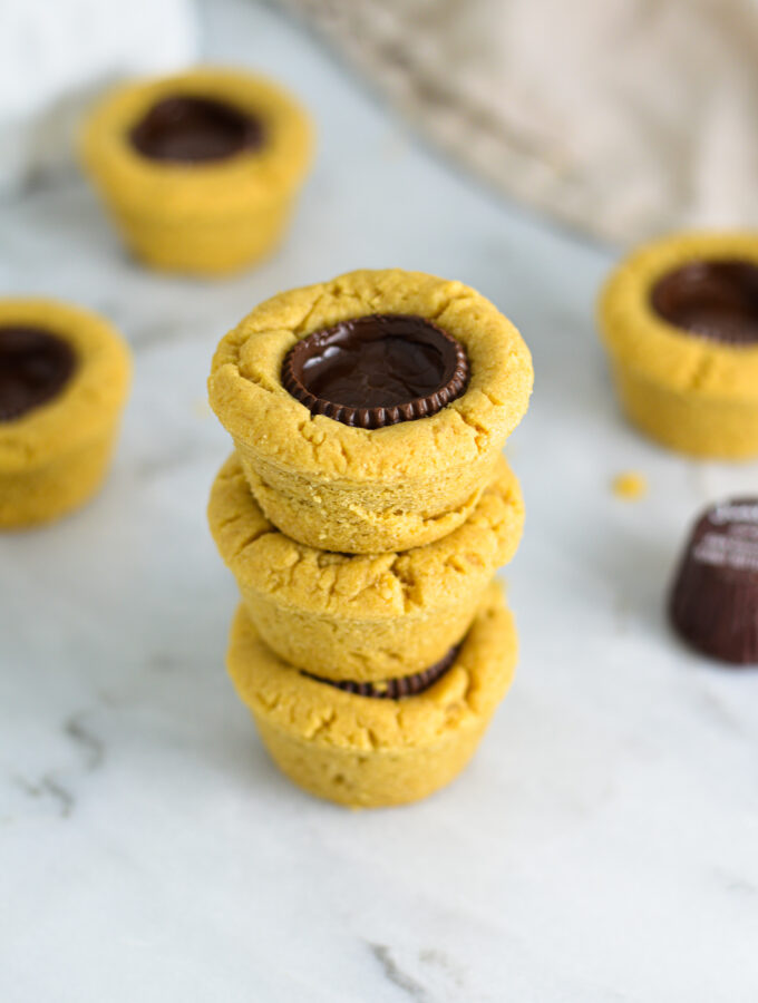 Some Dark Chocolate Peanut Butter Cookie Cups stacked with Justin's mini peanut butter cups in the background.