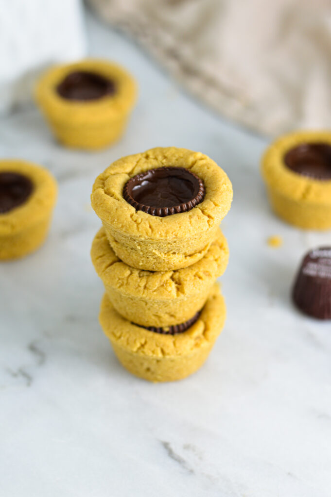 Some Dark Chocolate Peanut Butter Cookie Cups stacked with Justin's mini peanut butter cups in the background. 