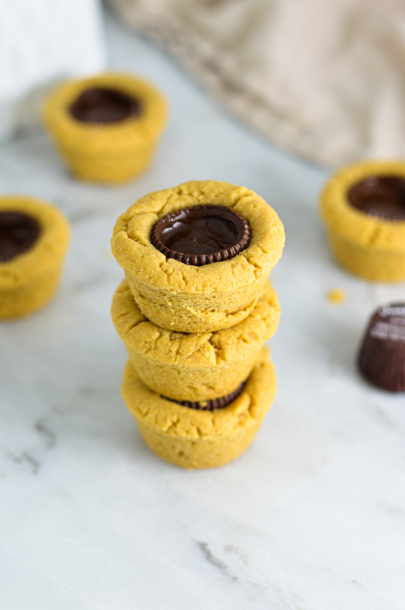 Some Dark Chocolate Peanut Butter Cookie Cups stacked with Justin's mini peanut butter cups in the background.