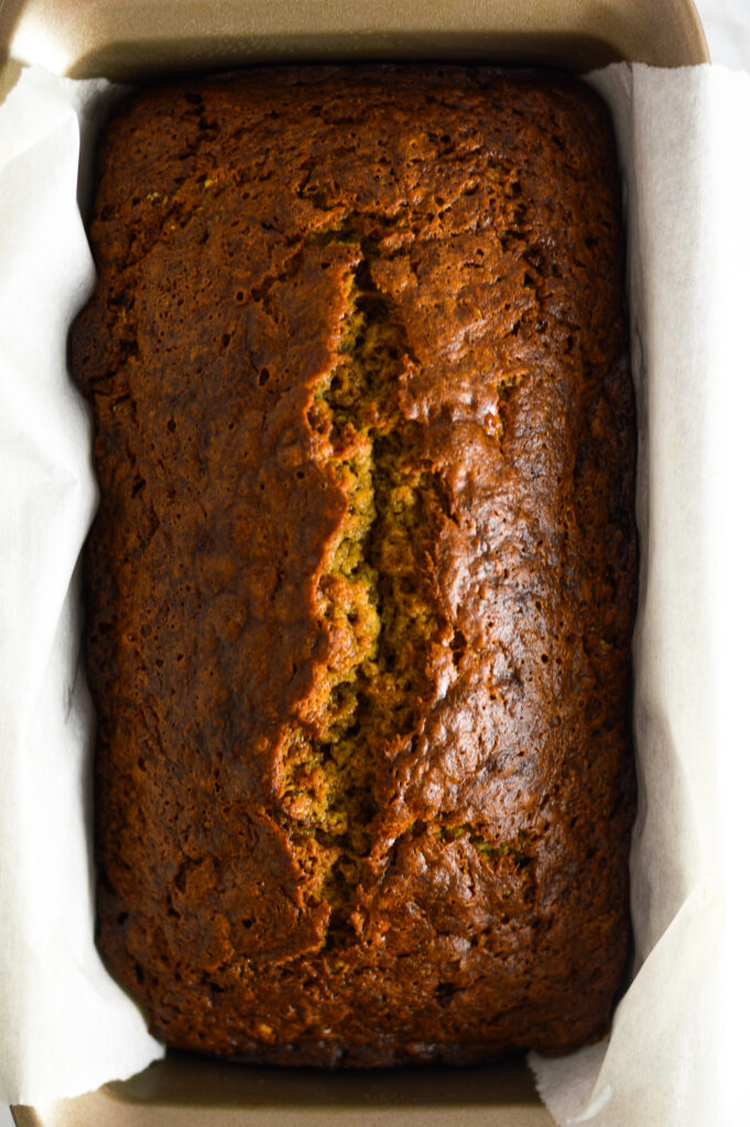 Overhead view of Ginger Banana Bread in a loaf pan lined with parchment paper.