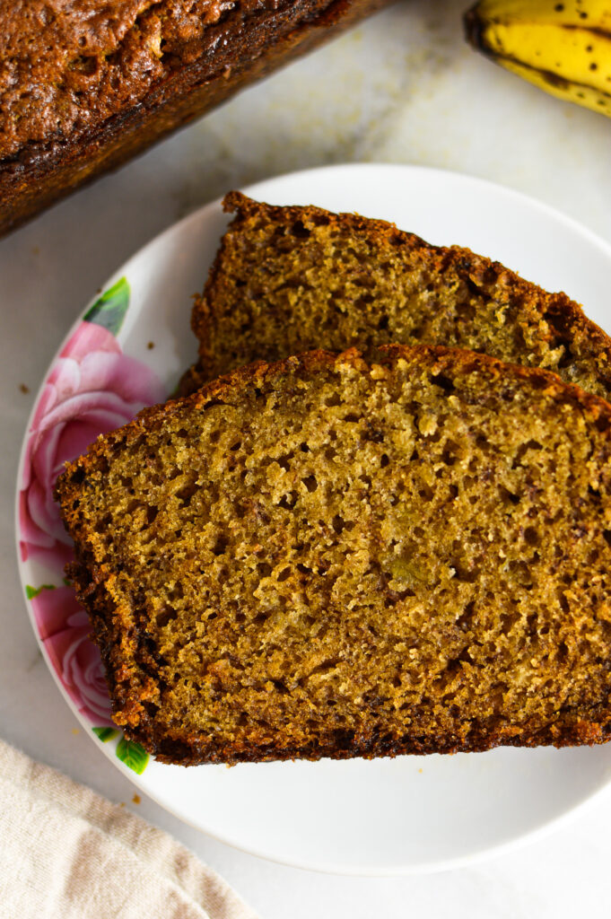 A closeup of two slices of Ginger Banana Bread on a white plate with pink flowers.