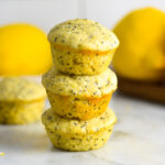 A stack of three Lemon Poppy Seed Mini Muffins on a granite surface.