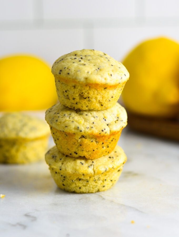 A stack of three Lemon Poppy Seed Mini Muffins on a granite surface.