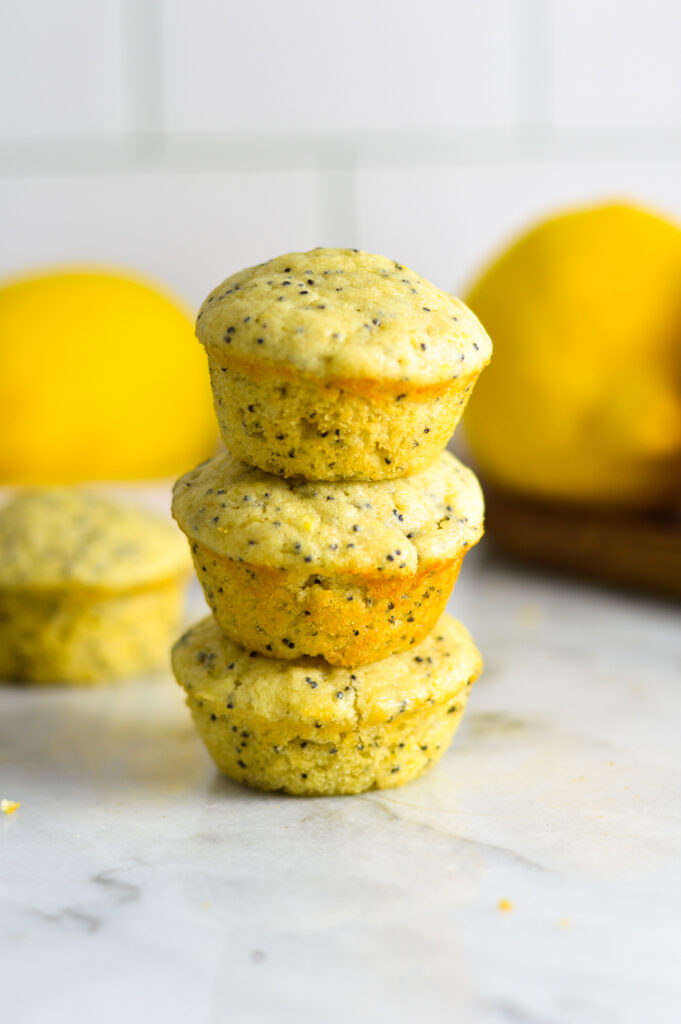 A stack of three Lemon Poppy Seed Mini Muffins on a granite surface.