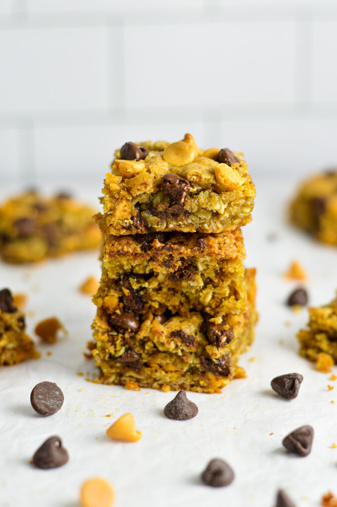 A stack of three Oatmeal Butterscotch Chocolate Chip Cookie Bars on a granite surface.