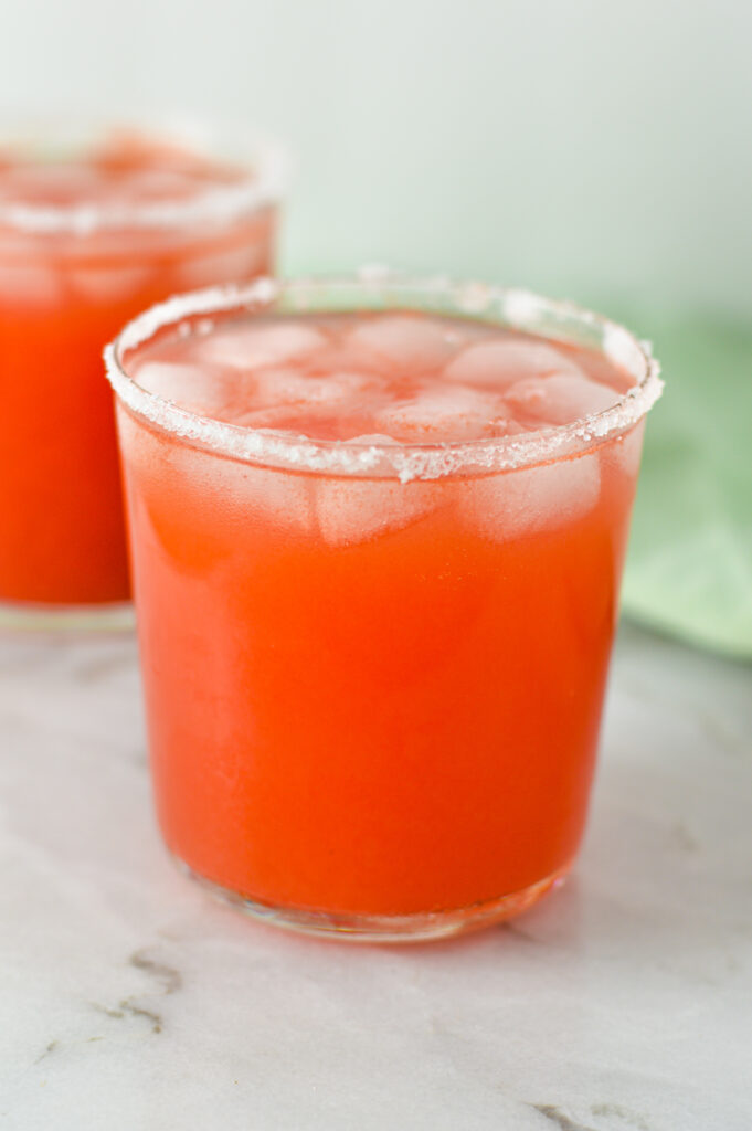 Two pink Watermelon Margaritas on ice on a white granite surface.