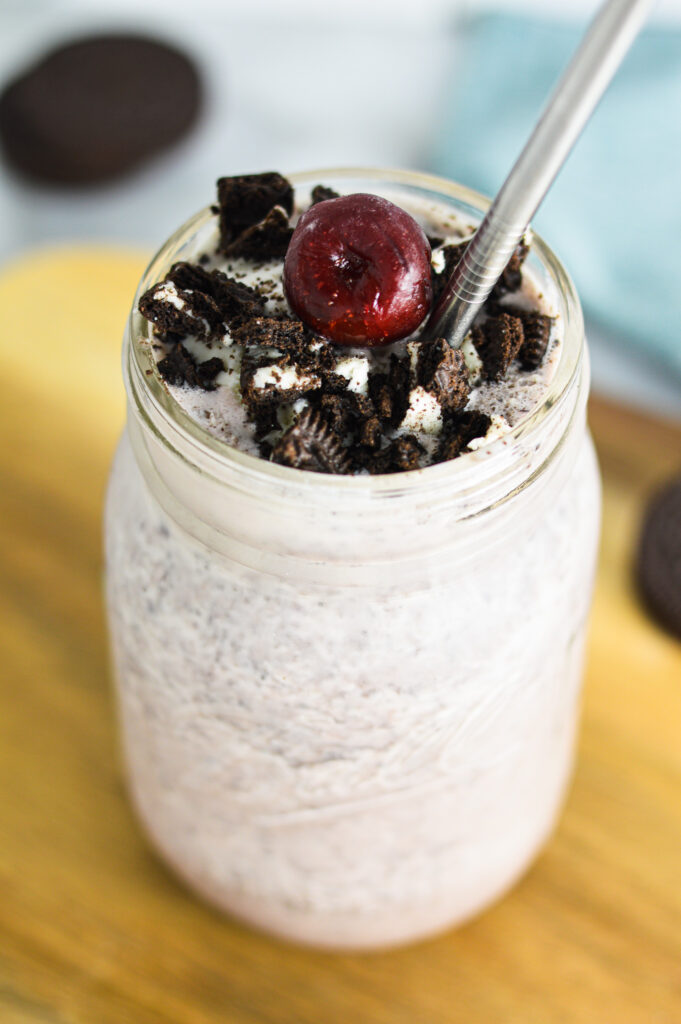 Cherry Oreo Milkshake in a mason jar with a metal straw in it.