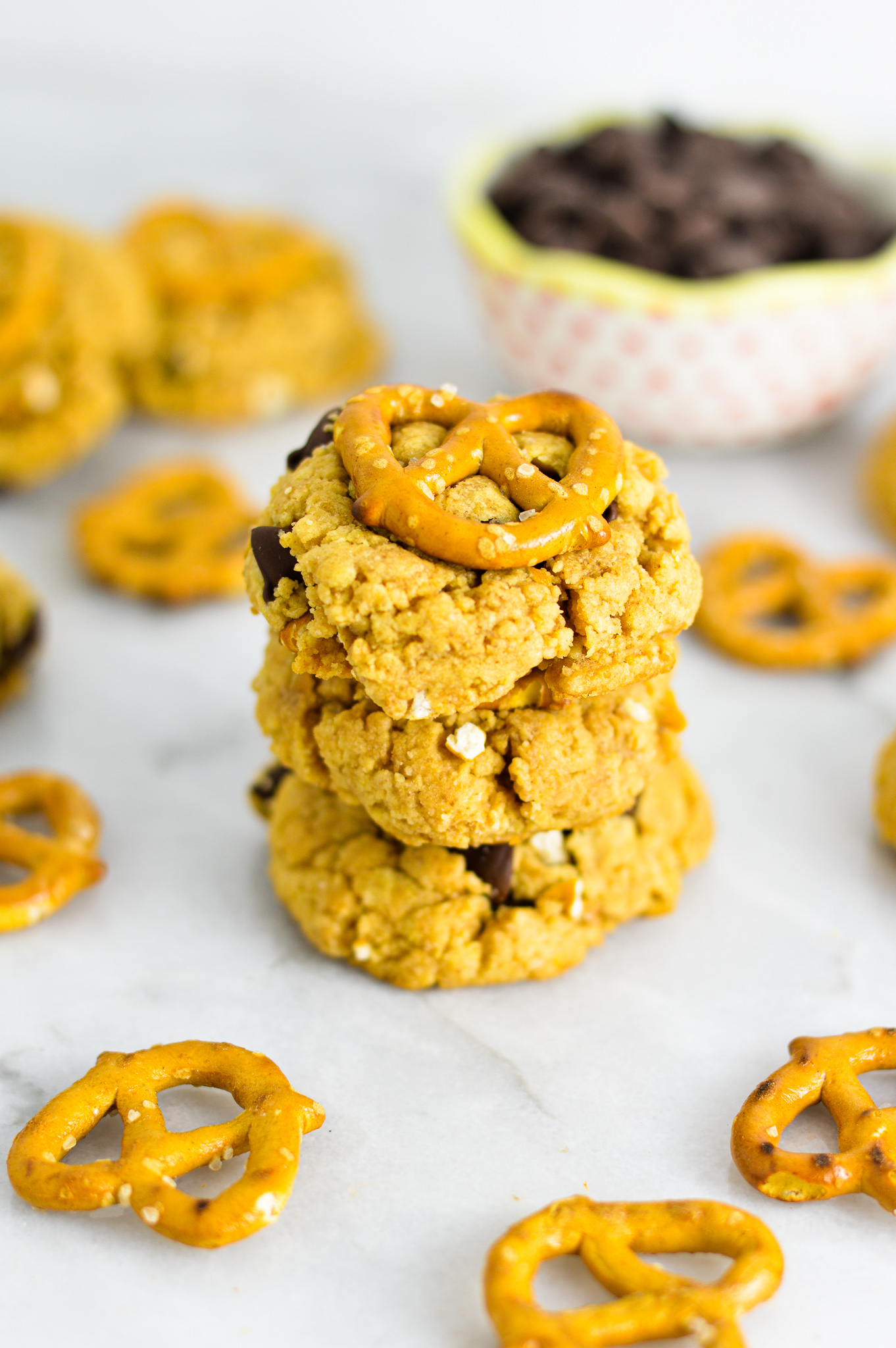 A stack of Chubby Hubby Cookies with a small bowl of chocolate chips in the background.