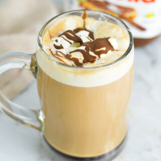 Nutella Mocha in a glass cup with a jar of Nutella in the background.