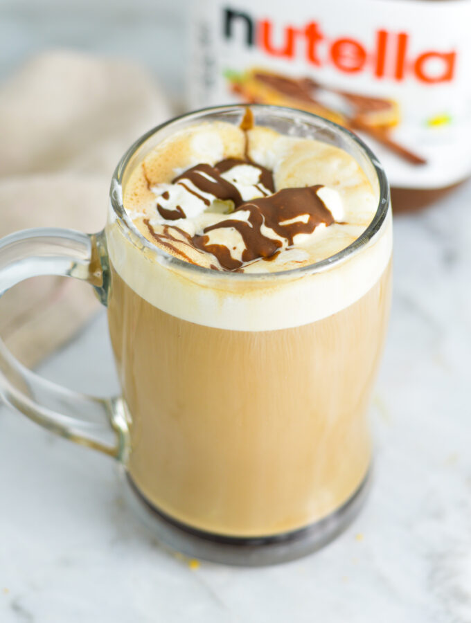 Nutella Mocha in a glass cup with a jar of Nutella in the background.