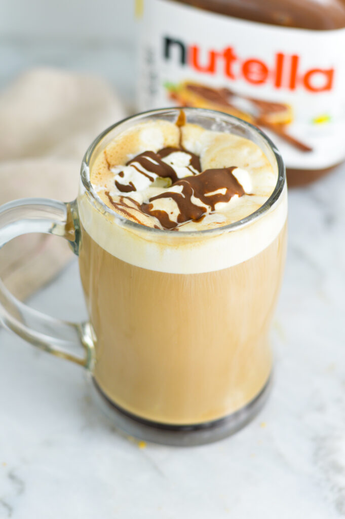 Nutella Mocha in a glass cup with a jar of Nutella in the background.