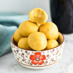 Peanut Butter Balls in a small bowl with a bite taken out of the top one.