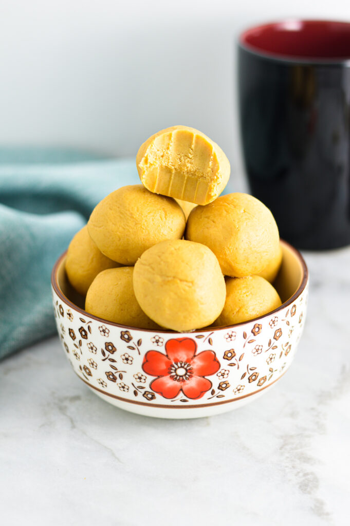 Peanut Butter Balls in a small bowl with a bite taken out of the top one.