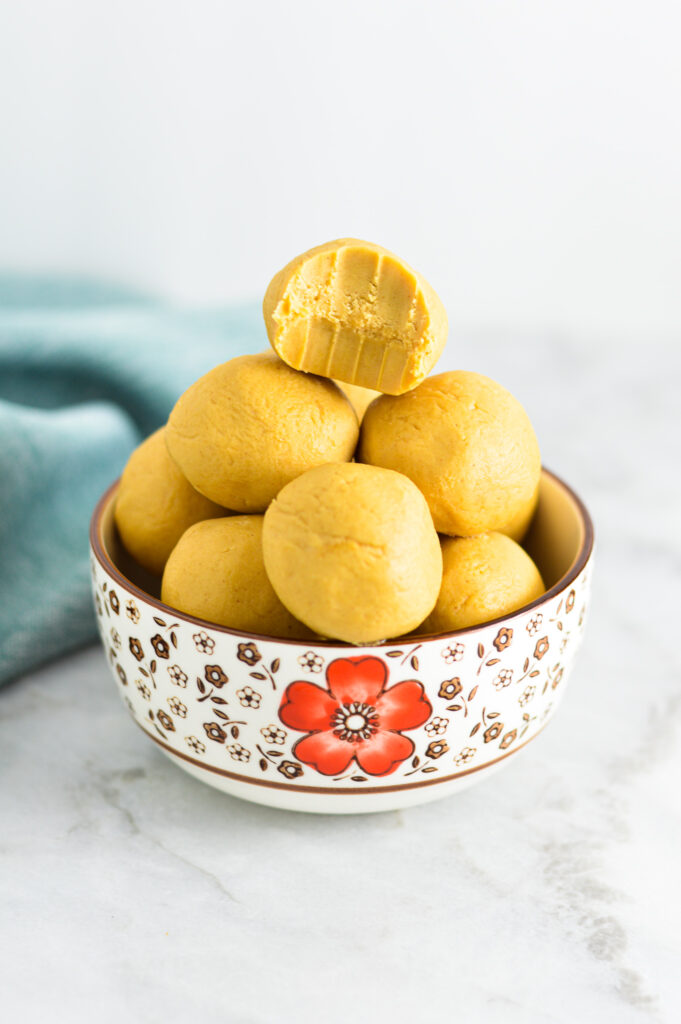 Peanut Butter Balls in a small bowl with a bite taken out of the top one.