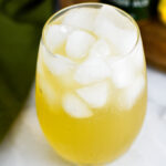 An ice filled glass with Sparkling Ginger Lemonade in it.