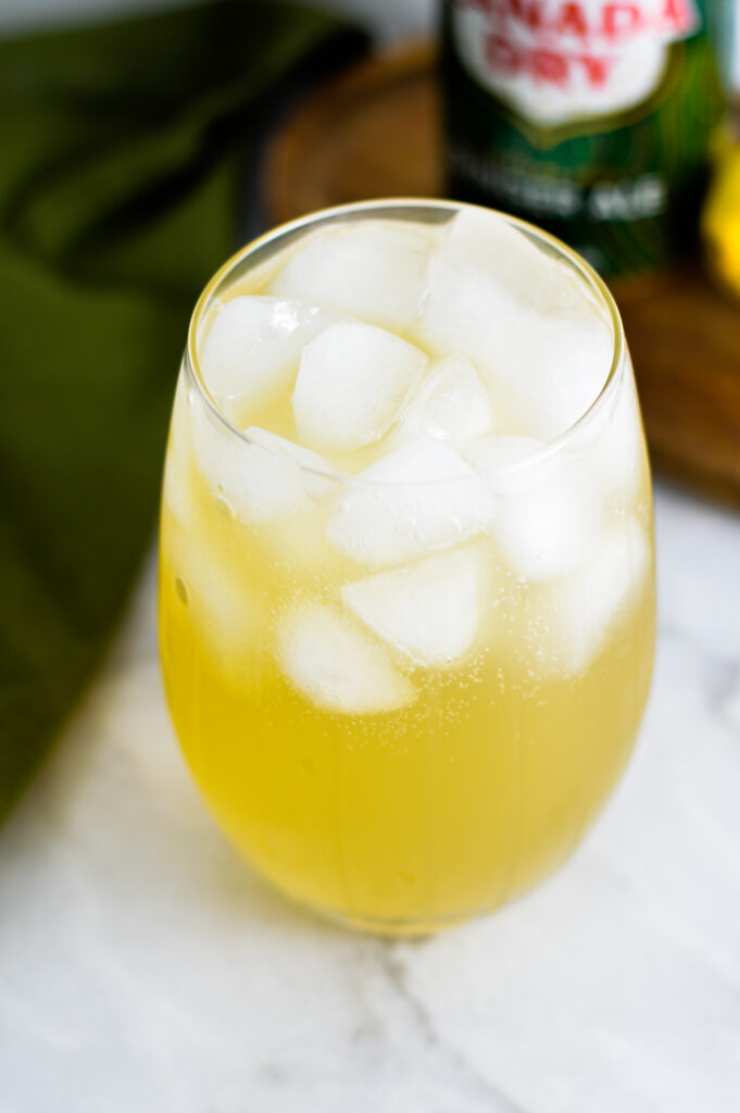 An ice filled glass with Sparkling Ginger Lemonade in it.