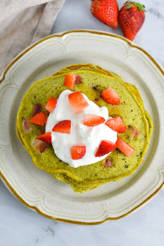 Overhead shot of Strawberry Matcha Pancakes with Greek yogurt and sliced strawberries on top.