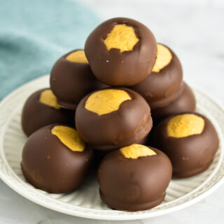 A stack of Buckeye peanut butter chocolate balls on a small white plate.