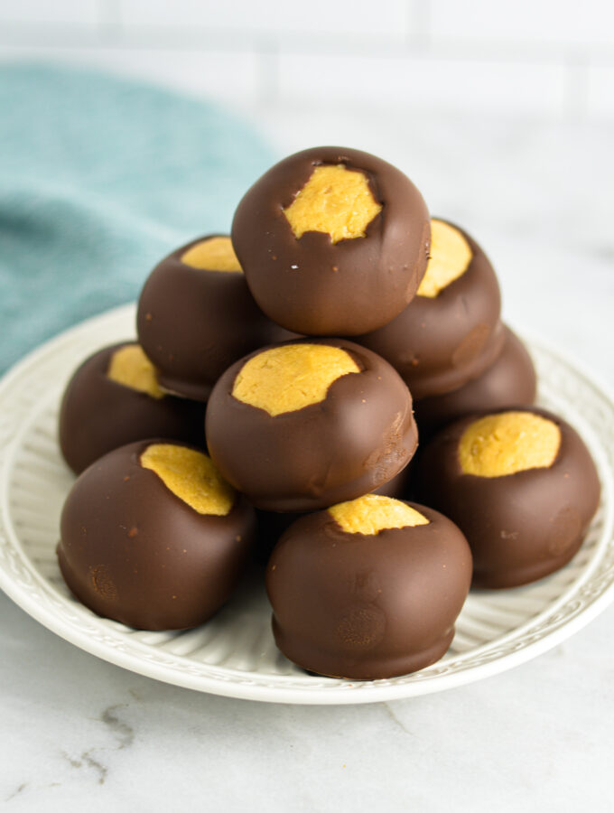 A stack of Buckeye peanut butter chocolate balls on a small white plate.