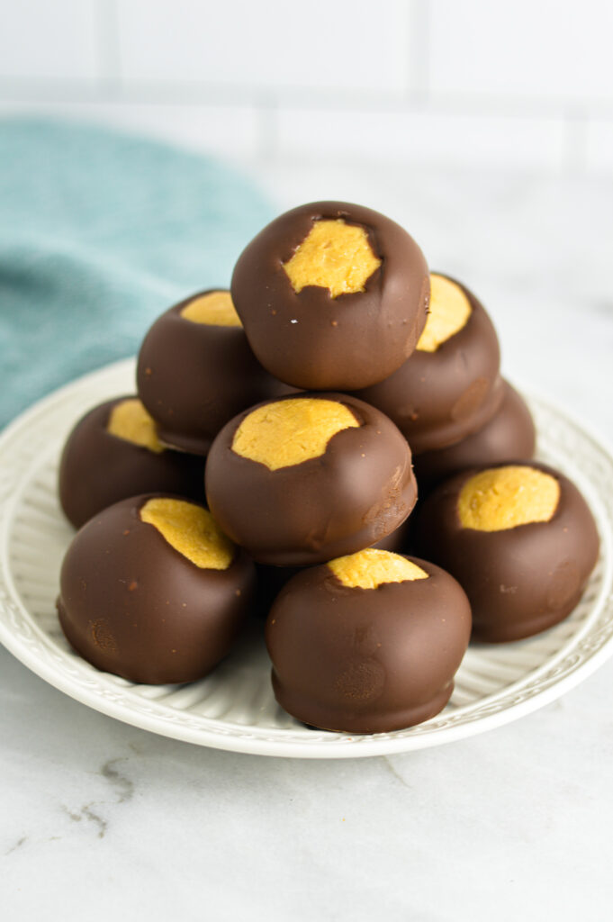 A stack of Buckeye peanut butter chocolate balls on a small white plate.