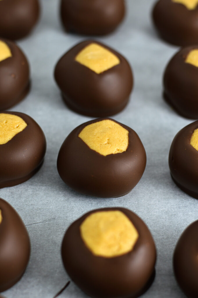 Buckeye chocolate peanut butter balls on a parchment paper lined baking sheet.