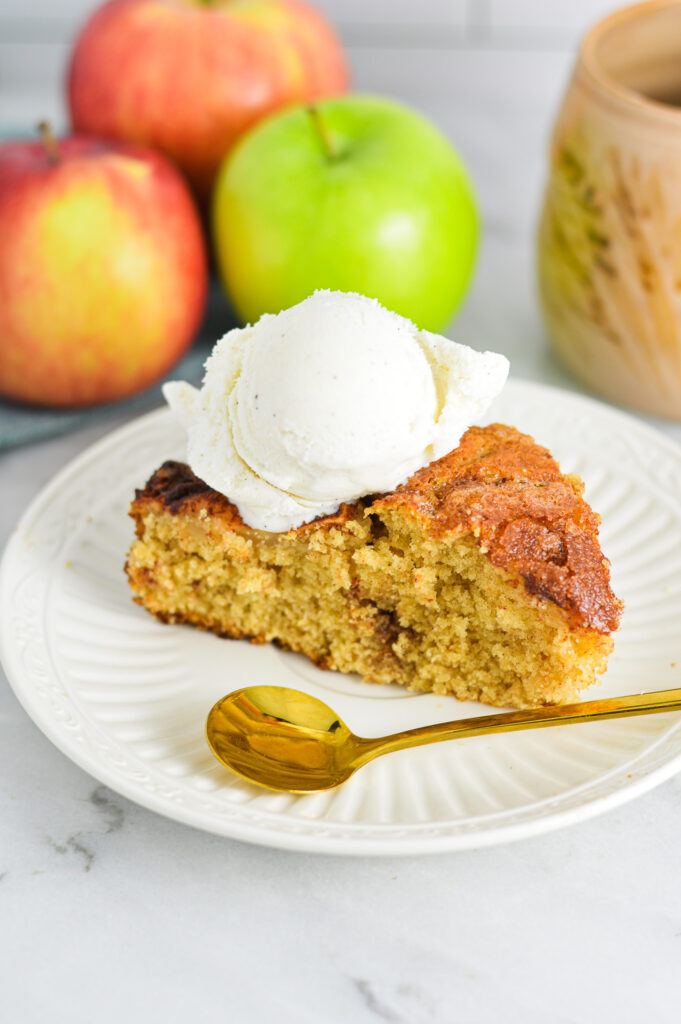 A slice of Dutch Apple Cake with a small gold spoon on a small white plate.