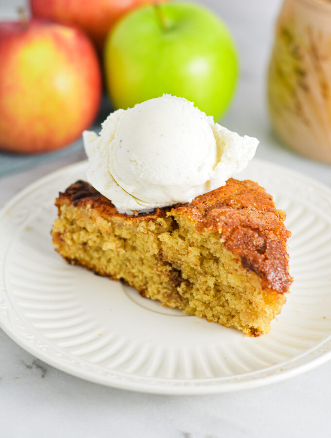 A slice of Dutch Apple Cake with a scoop of vanilla ice cream on top.