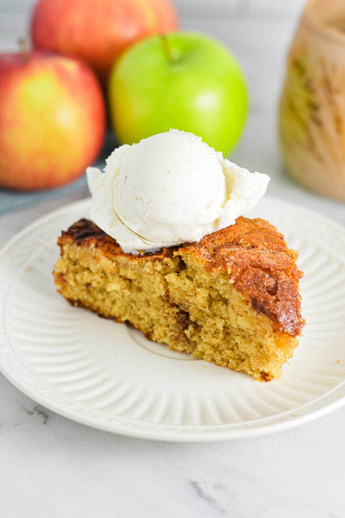 A slice of Dutch Apple Cake with a scoop of vanilla ice cream on top.