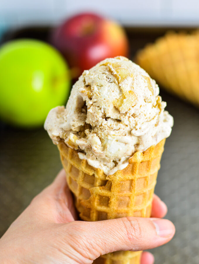 A hand holding No Churn Apple Cinnamon Ice Cream in a waffle cone.