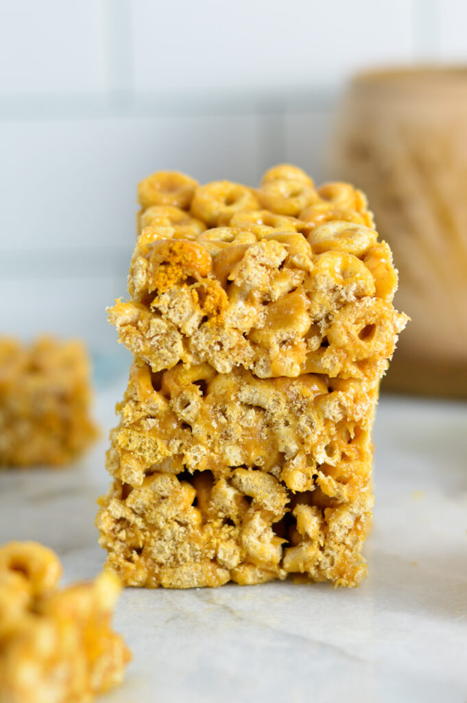 A stack of three Peanut Butter Cheerio Bars on a granite surface.