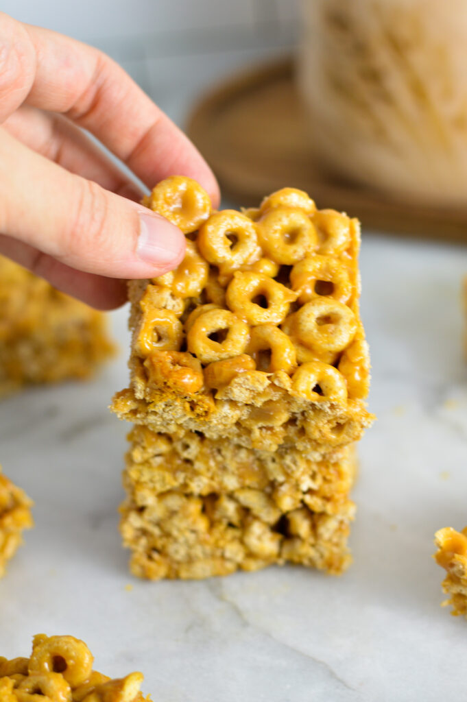 A hand taking a Peanut Butter Cheerio Bar from a stack of three.