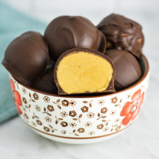 A small bowl filled with Peanut Butter Truffles, with one of them sliced in half.