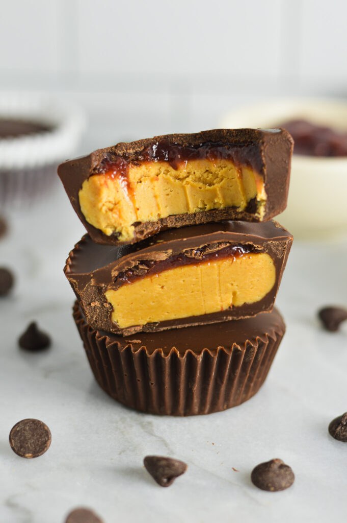 A stack of Peanut Butter and Jelly Chocolate Cups with a bite taken out of the top cup.