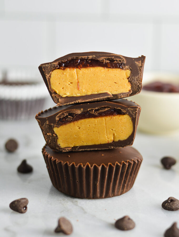 Peanut Butter and Jelly Chocolate Cups cut to reveal a creamy peanut butter filling and a thin jam layer on top.