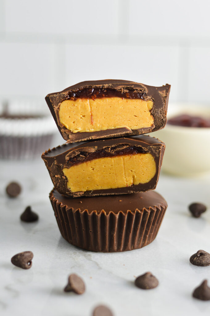 Peanut Butter and Jelly Chocolate Cups cut to reveal a creamy peanut butter filling and a thin jam layer on top.