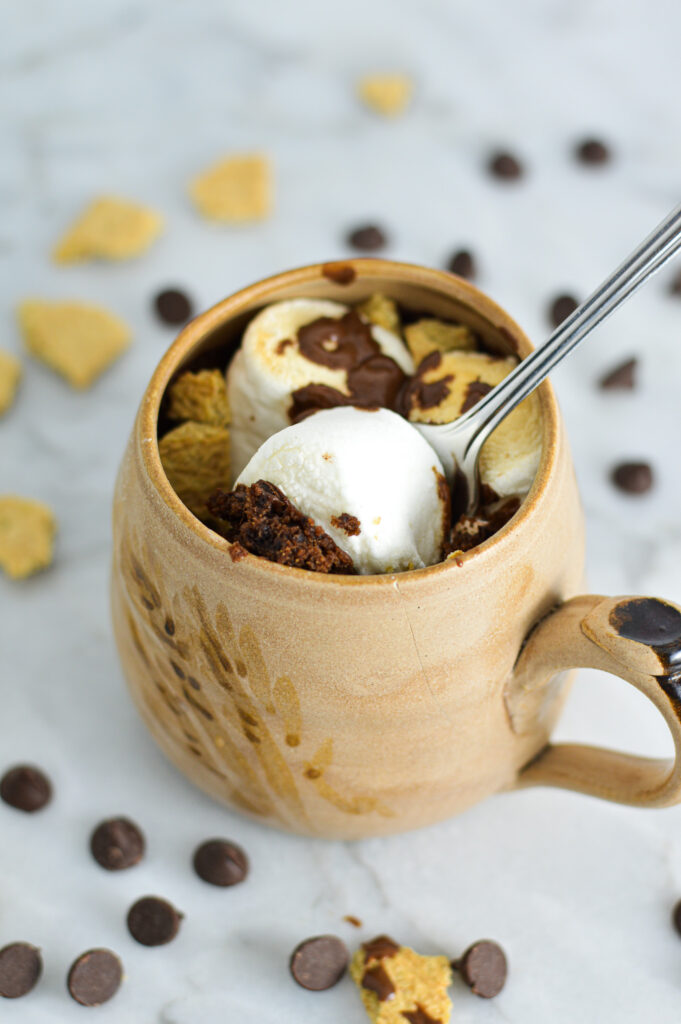 S'mores Mug Cake with a small spoon inside the beige ceramic mug.