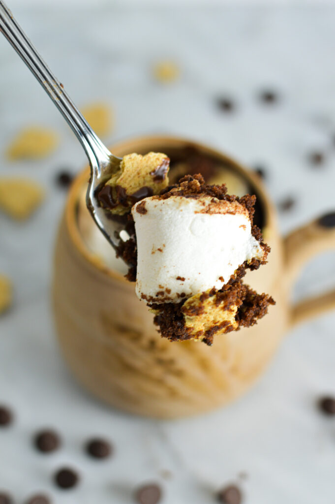 A spoonful of S'mores Mug Cake showing a large marshmallow and fluffy cake.