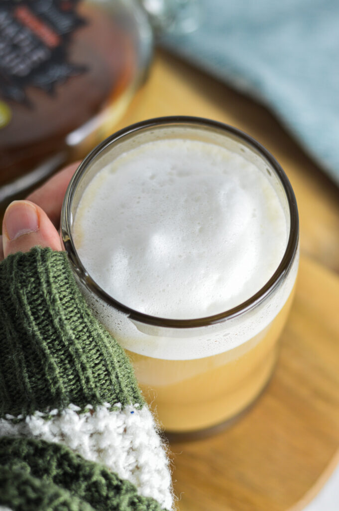 A hand holding a stein of creamy Maple Latte.