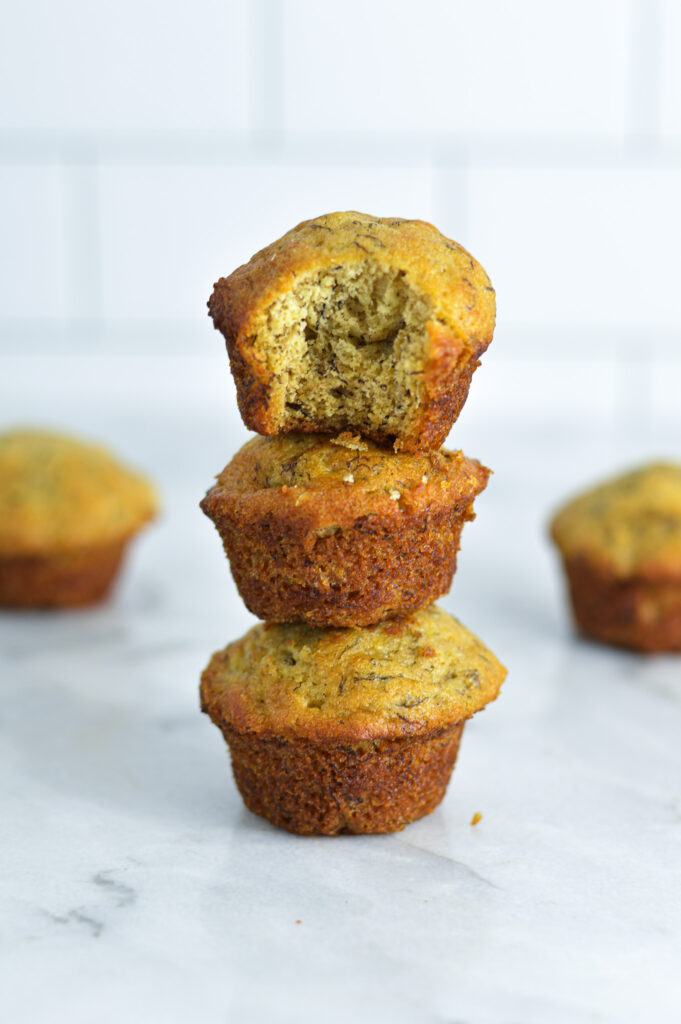 A stack of three Mini Banana Muffins with a bite taken out of the top one.