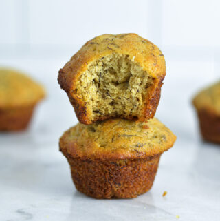 Two Mini Banana Muffins stacked on a white granite surface.