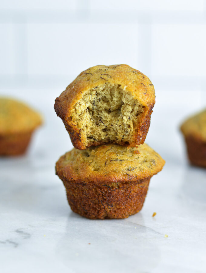 Two Mini Banana Muffins stacked on a white granite surface.