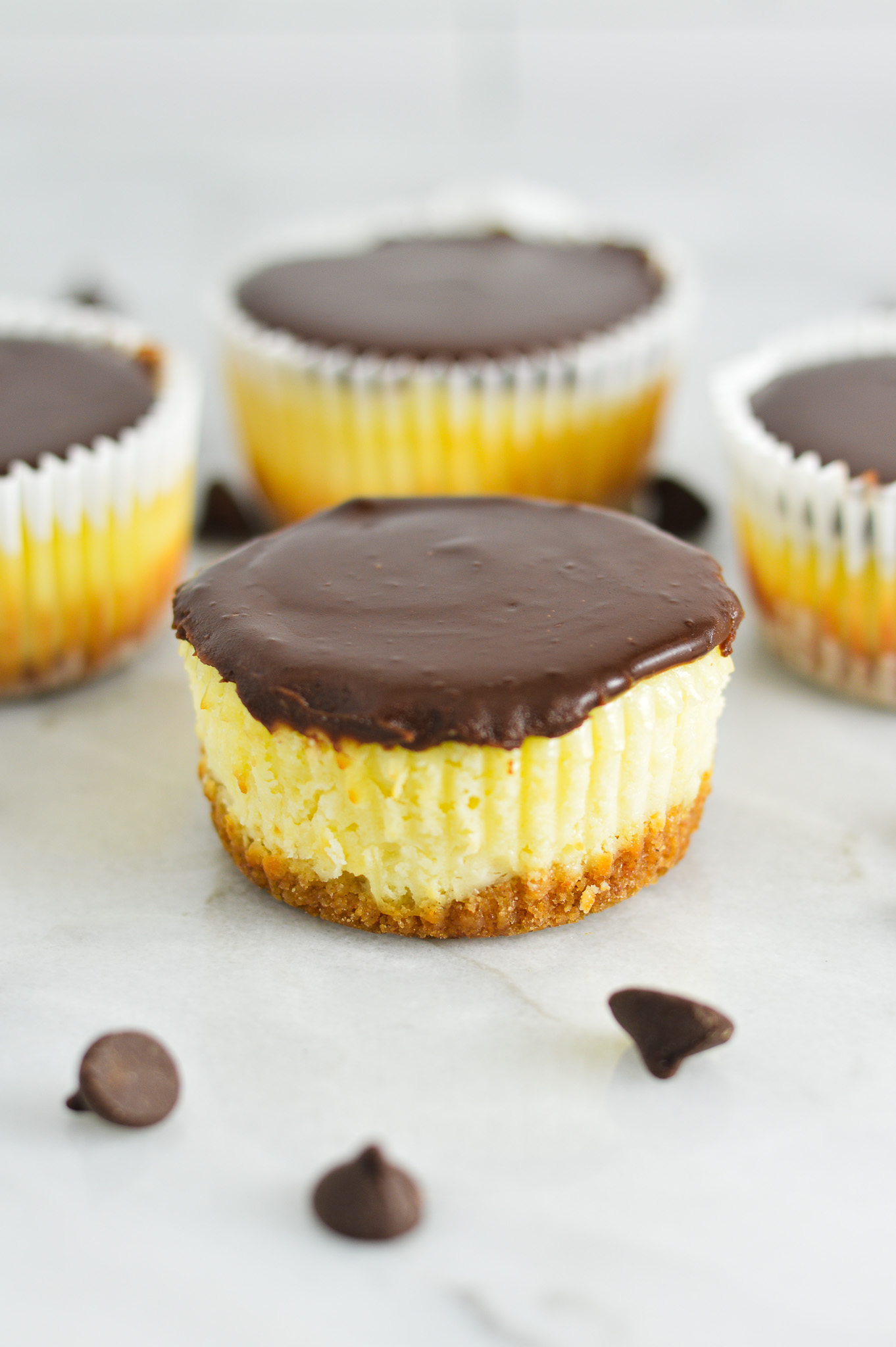 Creamy Mini Chocolate Ganache Cheesecakes with some cheesecakes without paper liners.