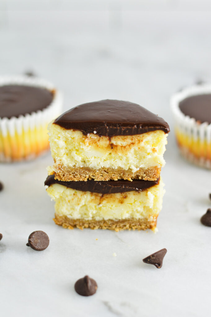 Mini Chocolate Ganache Cheesecake cut in two and stacked to show the chocolate layer, cheesecake layer and graham cracker crust.