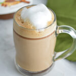 Nutella Latte with frothed milk on top and a jar of Nutella in the background.