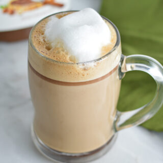 Nutella Latte with frothed milk on top and a jar of Nutella in the background.