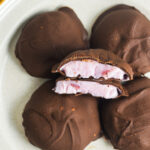 A closeup of 3 Ingredient Chocolate Yogurt Clusters arranged on a small plate. The creamy yogurt filling is surrounded by a hard chocolate shell.