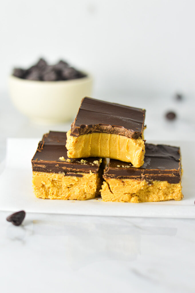 A stack of Buckeye Bars sliced into squares with a bite taken out of the top bar demonstrating the rich, indulgent layers.