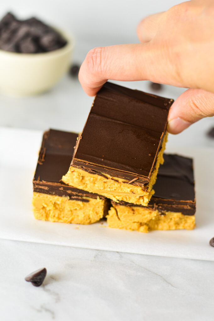 A hand reaching out to grab a Buckeye Bar, showing the rich chocolate hard shell.