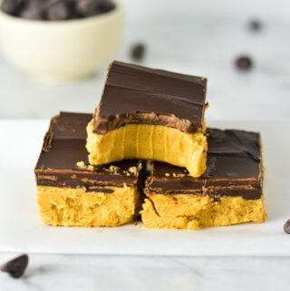 Rich Buckeye Bars neatly stacked with a bite taken out of the top no bake bar.